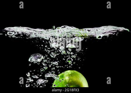 green apple falls into water on black background Stock Photo