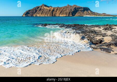 Galapagos beach landscape with strong waves, Stephens Bay with Witch Hill in background, San Cristobal island, Galapagos, Ecuador. Stock Photo