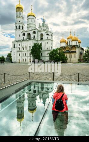 Girl tourist in Moscow Kremlin, Russia. Person looks at old Russian Orthodox cathedrals and churches in Moscow city center. View to young woman and la Stock Photo