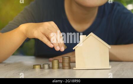 Abstract Investor puts coins stacked on the desk with mockup house concept auction value real estate investment wealth financial investment and busine Stock Photo