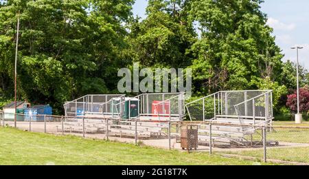 Empty metal bleacher seats next to a football field in Swissvale, Pennsylvania, USA on a sunny summer day Stock Photo