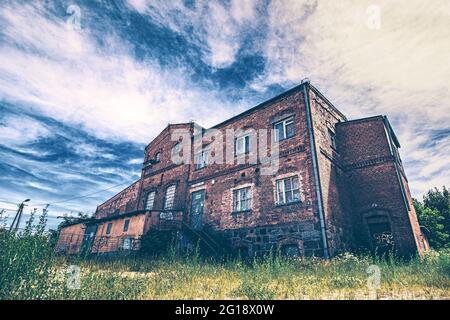 Monumental Lost Place horror house in bold colors. Abandoned building in the middle of nowhere disguised as an old, disused brewery and factory. Stock Photo