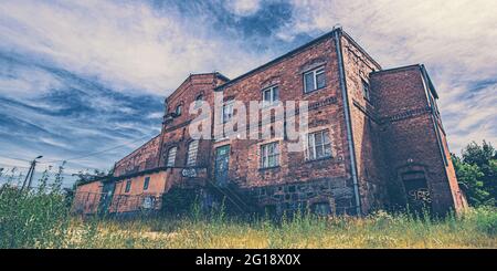 Monumental Lost Place horror house in bold colors. Abandoned building in the middle of nowhere disguised as an old, disused brewery and factory. Stock Photo