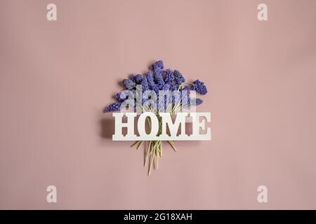 Minimalistic spring composition with blue flowers and the decorative word home. Stock Photo