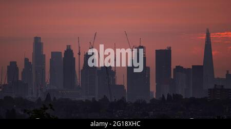 Wimbledon, London, UK. 6 June 2021. Skyscrapers in the centre of London silhouetted against an orange dawn sky. Credit: Malcolm Park/Alamy Live News Stock Photo