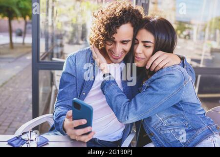 Arab couple looking at pictures taken with their smartphone outdoors Stock Photo