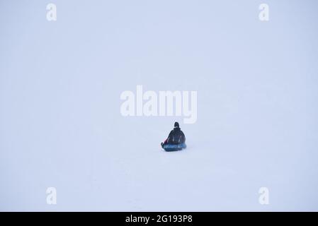 Man riding a tubing from a snowy mountain. Stock Photo