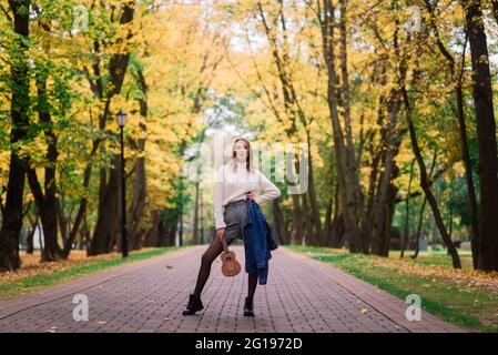 Beautiful woman playing ukulele guitar at outdoor in an autumn forest Stock Photo
