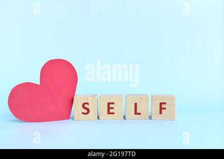 Self love and care concept. wooden blocks typography with big red heart shape cutout. Stock Photo