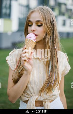 Young beautiful woman eats ice cream on a city walk on a sunny summer day on vacation Stock Photo
