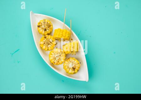 Corn, a snack made using ripe corn and garnished with chilli flakes and honey arranged in a white beautiful tableware  which is placed on a solid ice Stock Photo