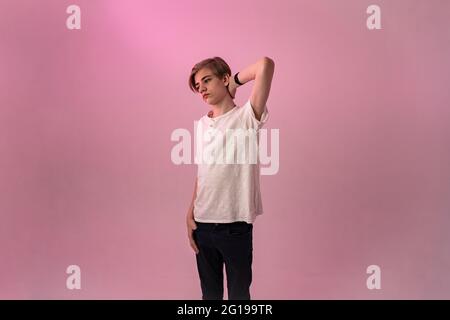 Emotional, low lighting shot of a teenage boy stressed about exams on a pink background. Stock Photo