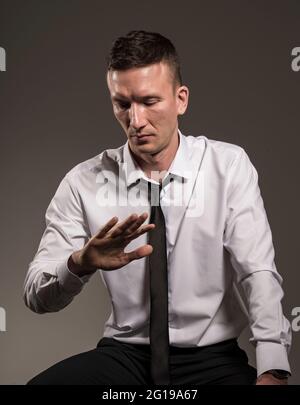 Man in a white shirt and tie looks at his hand. Stock Photo