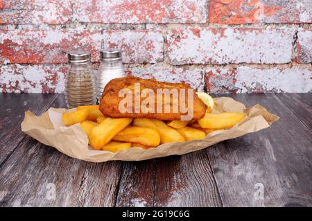 Battered cod fish and chips meal wrapped in brown paper Stock Photo