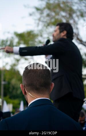 Bodyguard with communications earpiece looking over a politician as he speaks Stock Photo