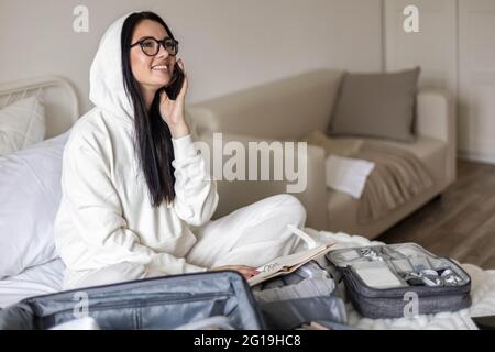 Smiling female talking use smartphone before leaving preparing to travel vacation or business trip Stock Photo