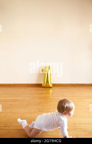 Little girl crawling on the floor against the background of an inflatable number one Stock Photo