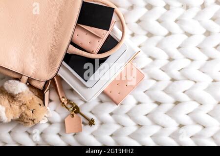 Top view composition organization storage of female handbag lying on white knitted plaid close up Stock Photo