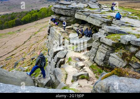 Crowds of walkers at Robin Hoods Cave, and Hope Valley seen from the popular gritstone cliff of Stanage Edge, Derbyshire, Peak District Stock Photo
