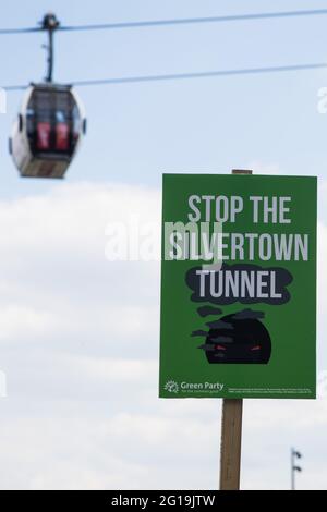 London, UK. 5th June, 2021. A Stop The Silvertown Tunnel placard is pictured beneath the Emirates Air Line cable car as environmental activists and local residents protest against the construction of the Silvertown Tunnel. Campaigners opposed to the controversial new £2bn road link across the River Thames from the Tidal Basin Roundabout in Silvertown to Greenwich Peninsula argue that it is incompatible with the UK's climate change commitments because it will attract more traffic and so also increased congestion and air pollution to London's most polluted borough. Credit: Mark Kerrison/Alamy Li Stock Photo