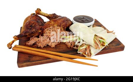 Aromatic half crispy duck with Chinese style pancakes and hoisin sauce on a wooden board isolated on a white background Stock Photo