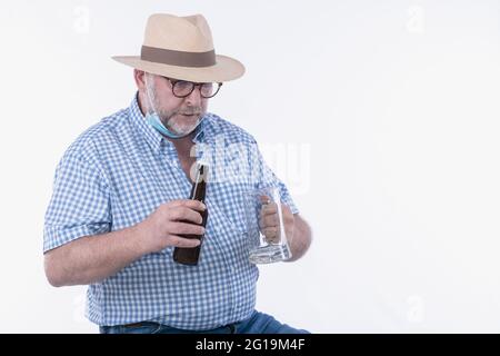 Mature man excitedly holding an empty beer glass and beer bottle: Selective focus. Leisure concept. Stock Photo