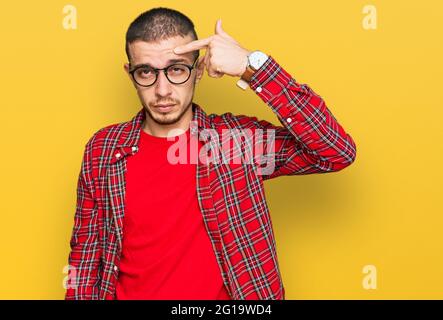 Hispanic young man wearing casual clothes pointing unhappy to pimple on forehead, ugly infection of blackhead. acne and skin problem Stock Photo