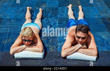 Successful retirement recreation, summer vacation concept. Retired mature couple enjoying beautiful sunny day in swimming pool at beach club. Stock Photo