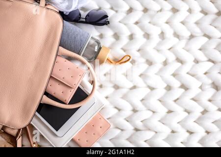 Top view composition organization storage of female handbag lying on white knitted plaid close up Stock Photo