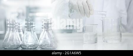 scientist in white coat poring water into glass beaker in medical laboratory science banner background Stock Photo