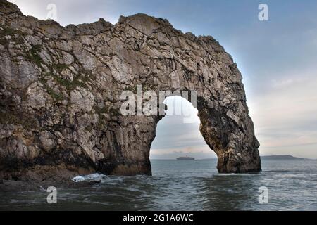 A close-up of Durdle Door archway with a steamship positioned perfectly in the middle of the horizon Stock Photo