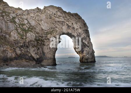 A close-up of Durdle Door archway with a steamship positioned perfectly in the middle of the horizon Stock Photo