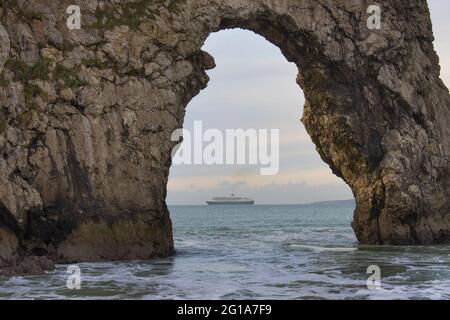 A close-up of Durdle Door archway with a steamship positioned perfectly in the middle of the horizon Stock Photo