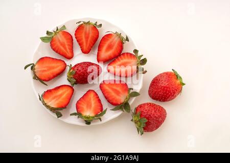 Closeup top view of red freshly harvested Strawberries,Fragaria   displayed in glass dishes isolated against white background , Stock Photo
