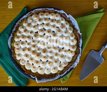 Lemon Pie with merengue on two green napkins decorated with a cake spatula server. Top View Stock Photo