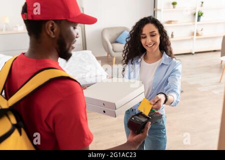 Black delivery man holding POS machine for payment Stock Photo