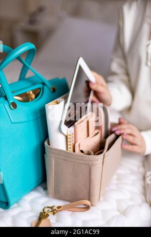 Elegant woman putting tablet into removable felt organizer for comfortable storage in female handbag Stock Photo