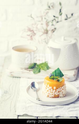Piece of mango mousse cake on plate over white wooden table. Stock Photo