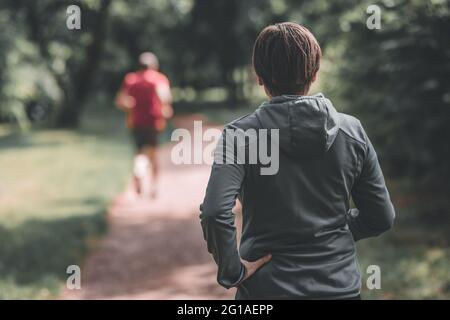 Rear view of adult female jogger in park ready for running on the track, healthy lifestyle and recreational activity in 40s Stock Photo