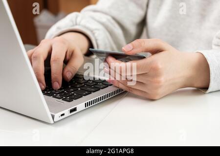 Woman uses laptop for paying online purchase within credit card. Shopping via internet and getting cashback.  Stock Photo