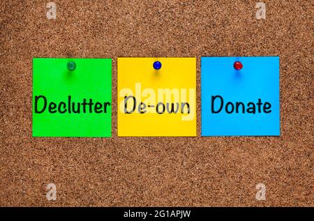 Three colored notes on corkboard with words Declutter, De-own, Donate. Close-up Stock Photo