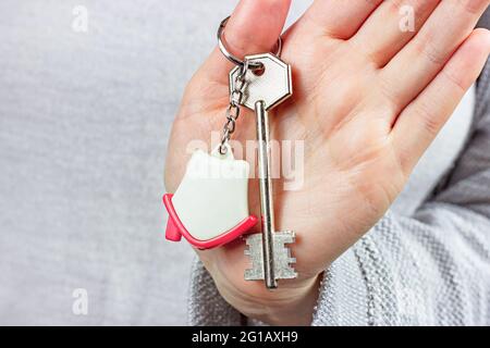 Caucasian woman hands holding the keychain with the keys and small house key ring close up. Apartment renter, real estate ownership, property purchase Stock Photo