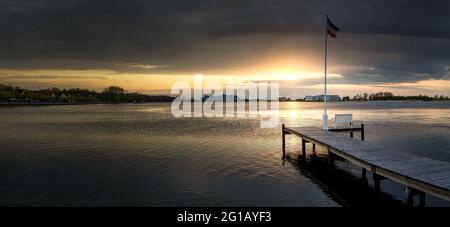 Wooden jetty by a small lake at sunset Stock Photo