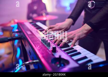 Hands of young woman touching keys of synthesizer during repetition Stock Photo