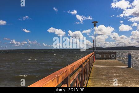 Promenade and jetty on the beach of Tsarnowice Lake in Poland on a warm summer day. On the shore of a beautiful bay and fishing spot. Stock Photo