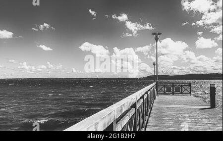 Promenade and jetty on the beach of Tsarnowice Lake in Poland on a warm summer day. On the shore of a beautiful bay and fishing spot. Stock Photo