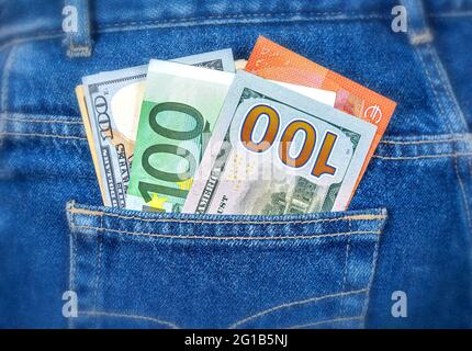 Various banknotes of Euro and american currency sticking out of the jeans pocket. Money in jeans pocket for travel and shopping Stock Photo