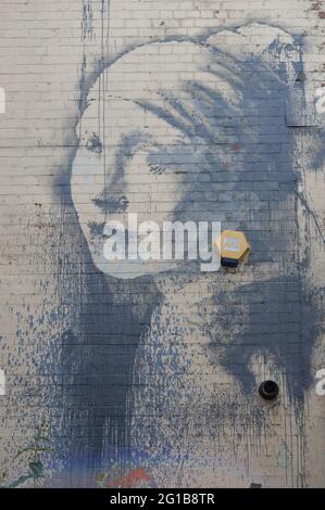 Bristol, UK. 3 June 2021. Banksy Mural 'The Girl with the Pierced Eardrum', based around a burglar alarm which is appeared on the side of a building. Stock Photo