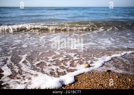 Small waves break on a beach of small pebbles at Charmouth in Dorset Stock Photo