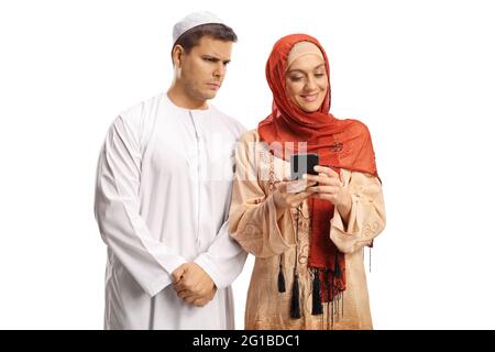 Angry muslim husband looking at the mobile phone of his wife isolated on white background Stock Photo